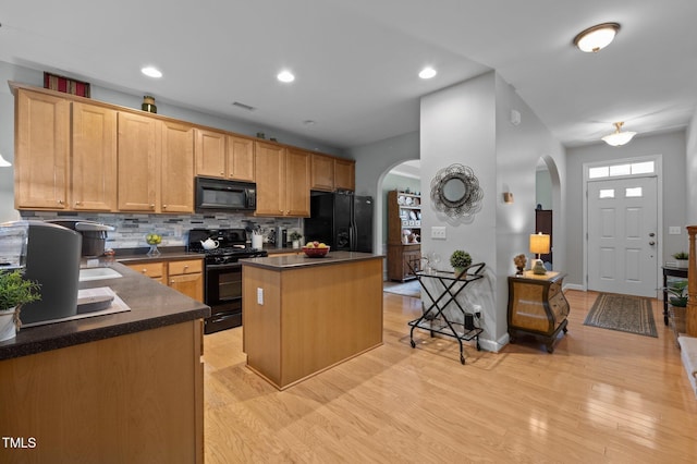 5216 Marcella Ct, Durham, NC 27707 - kitchen featuring black appliances, arched walkways, dark countertops, a kitchen island, and decorative backsplash
