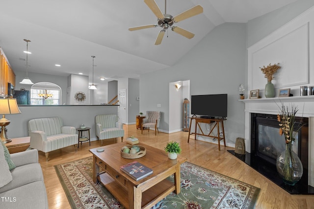 5216 Marcella Ct, Durham, NC 27707 - living room with a ceiling fan, a glass covered fireplace, lofted ceiling, stairway, and light wood finished floors