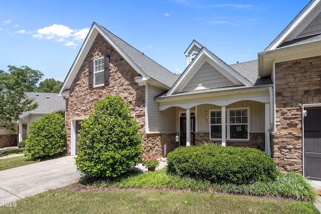 5216 Marcella Ct, Durham, NC 27707 - craftsman-style home featuring stone siding, driveway, roof with shingles, covered porch, and a garage