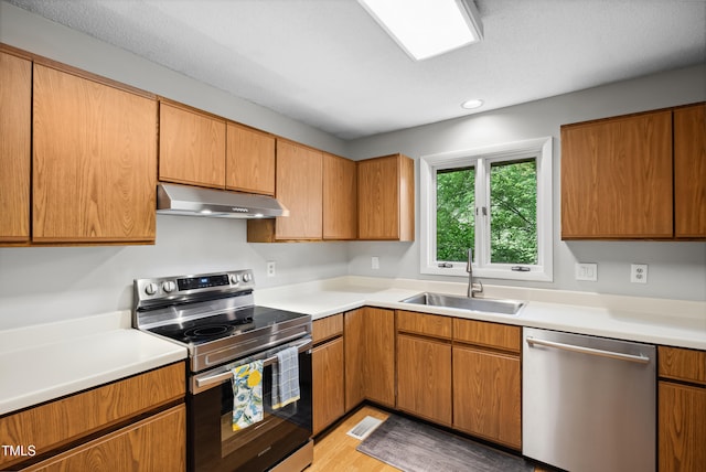 113 Twisted Oak Pl, Durham, NC 27705 - kitchen featuring appliances with stainless steel finishes, under cabinet range hood, light countertops, light wood-type flooring, and recessed lighting
