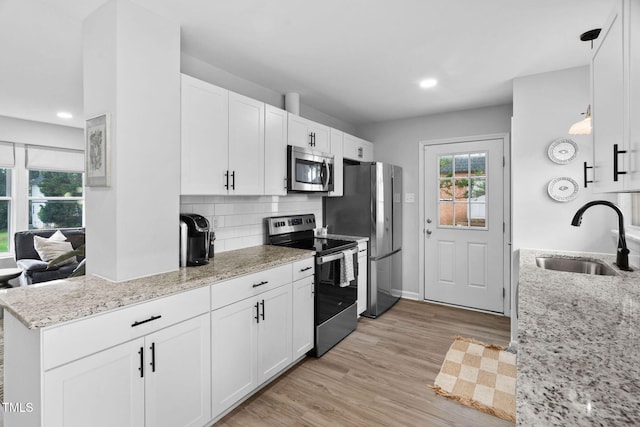 5400 Kaplan Dr, Raleigh, NC 27606 - kitchen featuring appliances with stainless steel finishes, light wood-type flooring, white cabinetry, decorative backsplash, and light stone counters