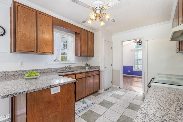 2312 Buckstone Ct, Fuquay Varina, NC 27526 - kitchen with crown molding, brown cabinetry, light tile patterned flooring, a chandelier, and a peninsula