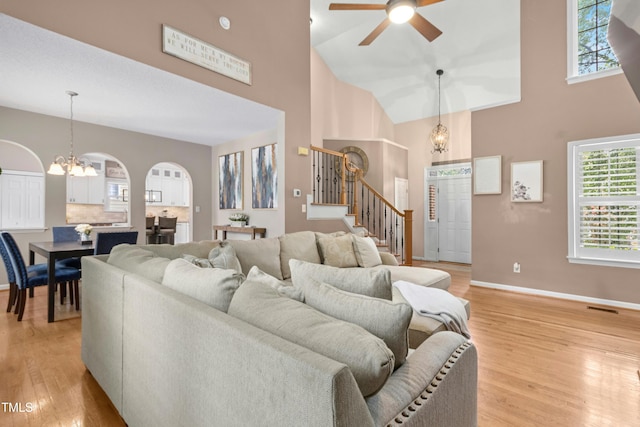 5301 Denmead Way, Raleigh, NC 27613 - living room with stairs, a high ceiling, a chandelier, light wood-style floors, and arched walkways