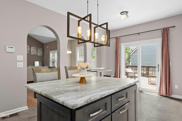 5301 Denmead Way, Raleigh, NC 27613 - kitchen featuring arched walkways, light countertops, hanging light fixtures, a center island, and lofted ceiling