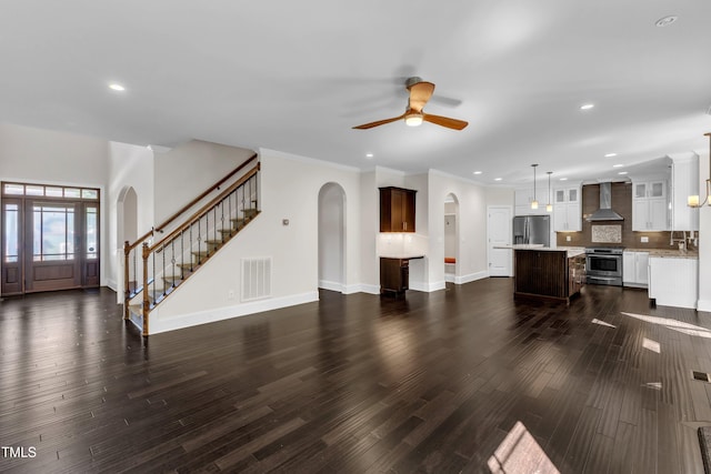 6332 Mountain Oaks Way, Wake Forest, NC 27587 - unfurnished living room with arched walkways, stairs, ceiling fan, dark wood finished floors, and recessed lighting