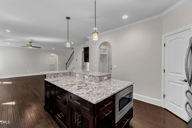 6332 Mountain Oaks Way, Wake Forest, NC 27587 - kitchen featuring stainless steel microwave, arched walkways, a ceiling fan, dark wood-style flooring, and crown molding