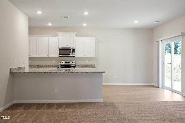 94 Taverners Ln, Angier, NC 27501 - kitchen with stainless steel appliances, light stone countertops, white cabinetry, light carpet, and recessed lighting
