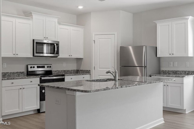 154 Taverners Ln, Angier, NC 27501 - kitchen featuring appliances with stainless steel finishes, white cabinetry, light wood-style flooring, light stone countertops, and an island with sink