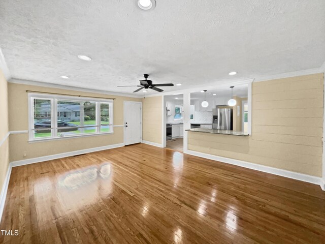 3205 Marita Dr, Fayetteville, NC 28301 - unfurnished living room with a textured ceiling, crown molding, wood finished floors, and a ceiling fan