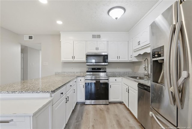 3511 Rolls Ave, Fayetteville, NC 28311 - kitchen featuring appliances with stainless steel finishes, a peninsula, light wood-style floors, white cabinetry, and a textured ceiling