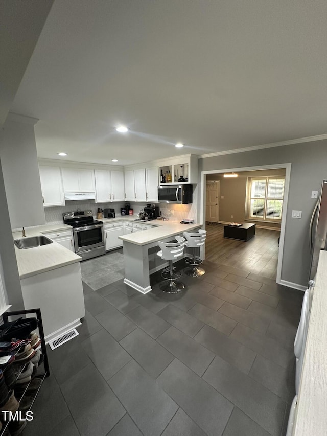 5809 Iris Lake Ct, Raleigh, NC 27604 - kitchen with appliances with stainless steel finishes, a peninsula, decorative backsplash, recessed lighting, and white cabinetry