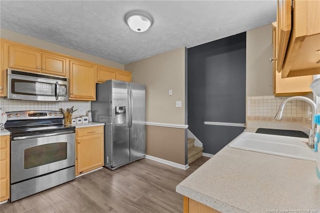 3117 Winesap Rd, Hope Mills, NC 28348 - kitchen with stainless steel appliances, light countertops, light wood-style floors, light brown cabinets, and a textured ceiling