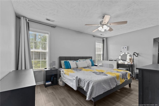 3117 Winesap Rd, Hope Mills, NC 28348 - bedroom featuring wood finished floors, multiple windows, a textured ceiling, and a ceiling fan