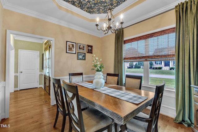 71 Smithsanders Ct, Smithfield, NC 27577 - dining space featuring a chandelier, crown molding, light wood-style flooring, a tray ceiling, and a wainscoted wall