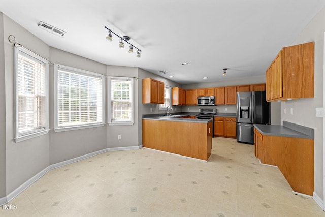 2037 Summer Shire Way, Raleigh, NC 27604 - kitchen featuring stainless steel appliances, a peninsula, brown cabinets, track lighting, and recessed lighting
