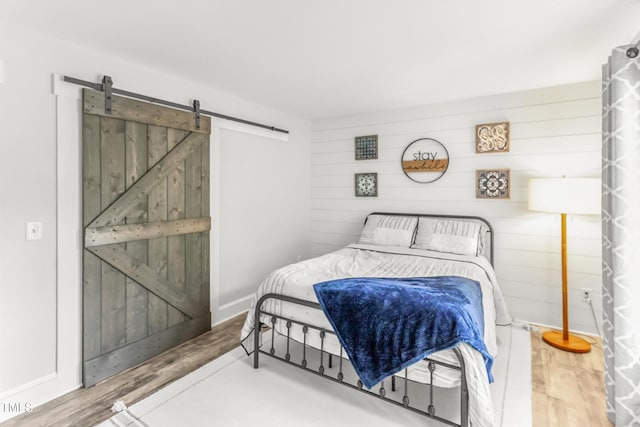 2218 Watersglen Dr, Apex, NC 27502 - bedroom featuring a barn door, wood finished floors, and wooden walls