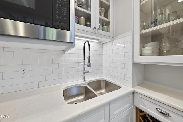 1500 River Mill Dr Unit 310, Wake Forest, NC 27587 - kitchen featuring stainless steel microwave, white cabinets, glass insert cabinets, decorative backsplash, and light stone countertops