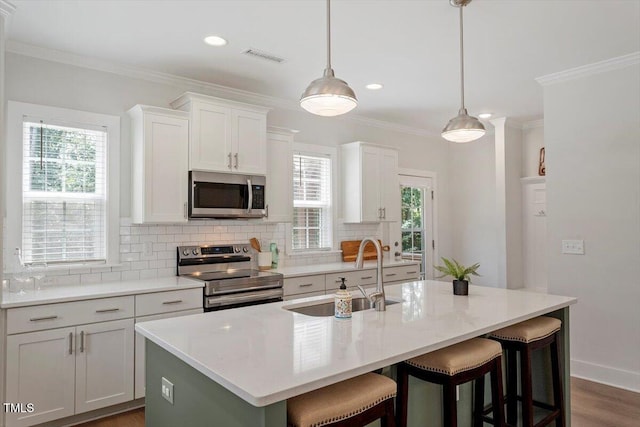 1304 Castlebay Rd, Durham, NC 27703 - kitchen with stainless steel appliances, tasteful backsplash, a kitchen breakfast bar, crown molding, and a center island with sink