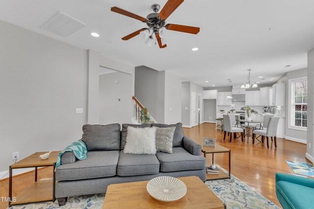 413 Westfalen Dr, Cary, NC 27519 - living room with a ceiling fan, light wood finished floors, recessed lighting, a chandelier, and stairs