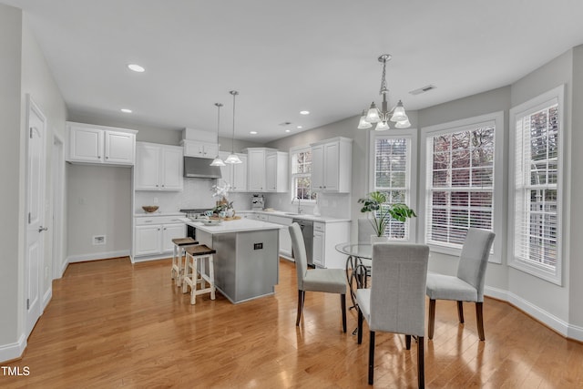 413 Westfalen Dr, Cary, NC 27519 - kitchen with under cabinet range hood, dishwasher, a center island, light countertops, and white cabinetry