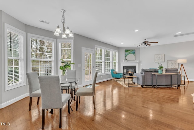 413 Westfalen Dr, Cary, NC 27519 - dining area with wood finished floors, a chandelier, a glass covered fireplace, ceiling fan, and recessed lighting