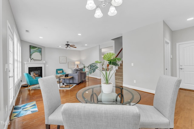 413 Westfalen Dr, Cary, NC 27519 - dining space with stairway, a glass covered fireplace, recessed lighting, a chandelier, and a ceiling fan