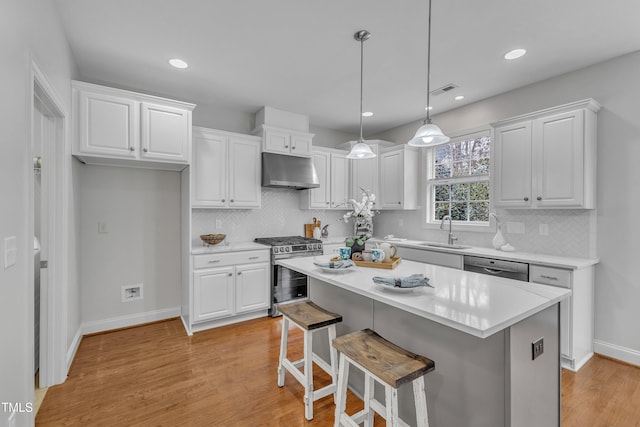 413 Westfalen Dr, Cary, NC 27519 - kitchen featuring appliances with stainless steel finishes, under cabinet range hood, white cabinets, light wood-style flooring, and recessed lighting