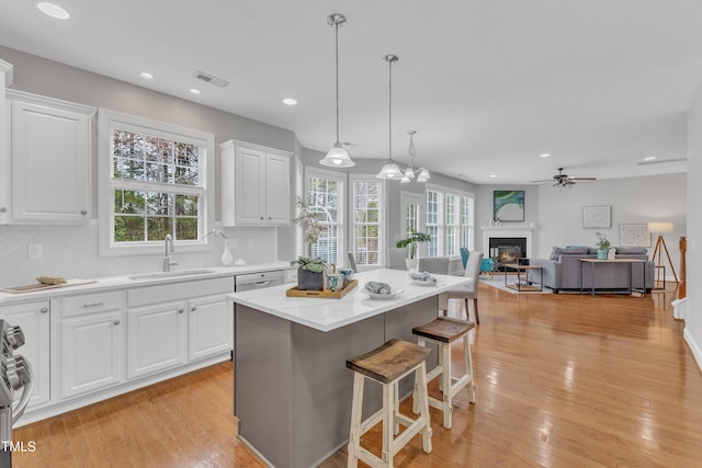 413 Westfalen Dr, Cary, NC 27519 - kitchen with a breakfast bar, a ceiling fan, light wood finished floors, a glass covered fireplace, and white cabinets