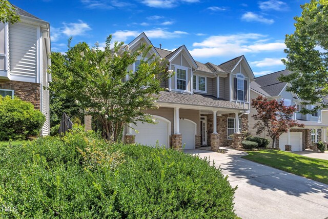 413 Westfalen Dr, Cary, NC 27519 - view of front facade featuring stone siding, a garage, concrete driveway, a shingled roof, and a porch