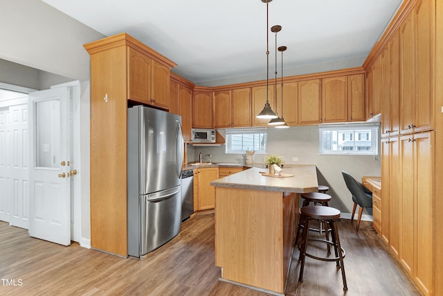 1821 Kelly Glen Dr, Apex, NC 27502 - kitchen with appliances with stainless steel finishes, wood finished floors, light countertops, a kitchen bar, and a kitchen island