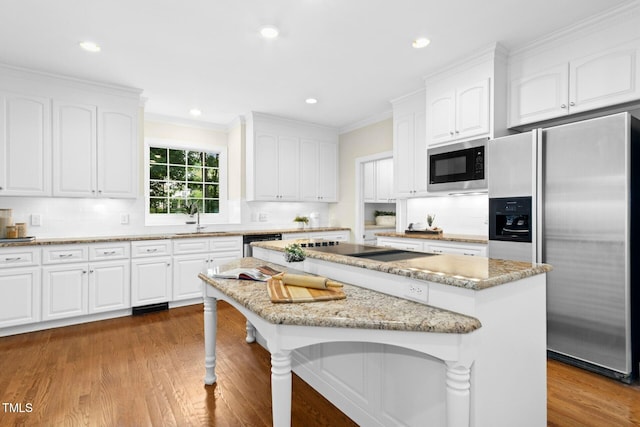 5204 Winter Holly Ct, Raleigh, NC 27606 - kitchen with black appliances, a center island, light stone countertops, crown molding, and white cabinetry