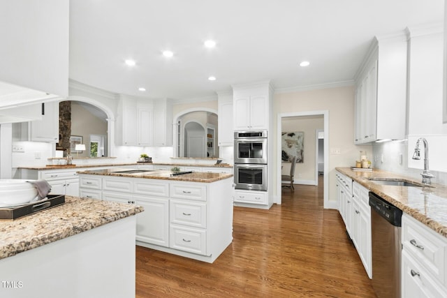 5204 Winter Holly Ct, Raleigh, NC 27606 - kitchen with stainless steel appliances, arched walkways, white cabinets, wood finished floors, and ornamental molding