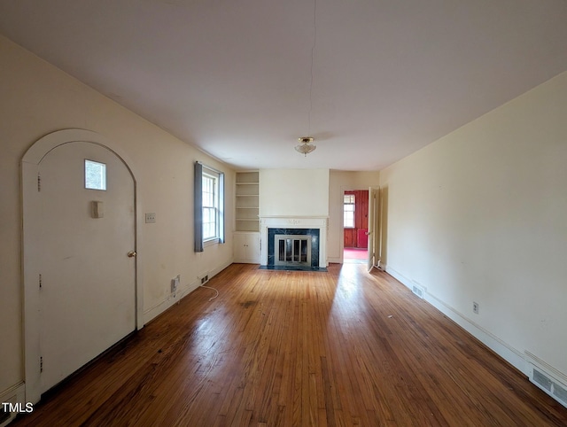 2705 Royster St, Raleigh, NC 27608 - unfurnished living room with hardwood / wood-style floors, a fireplace with flush hearth, and built in features