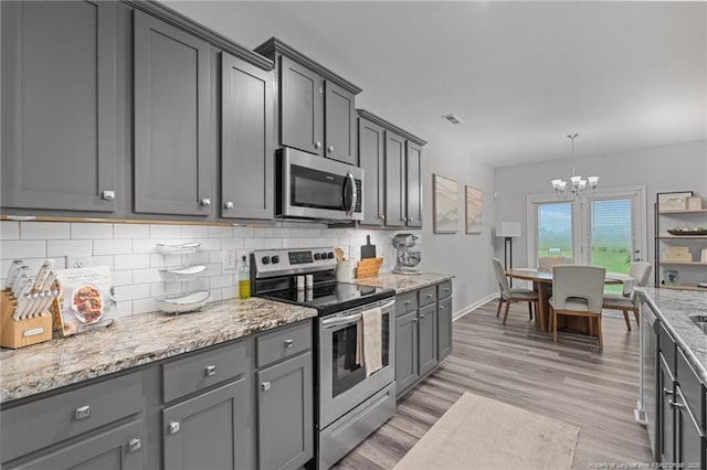 115 Doubletree Ln, Autryville, NC 28318 - kitchen with stainless steel appliances, a chandelier, decorative backsplash, gray cabinets, and light wood-style flooring