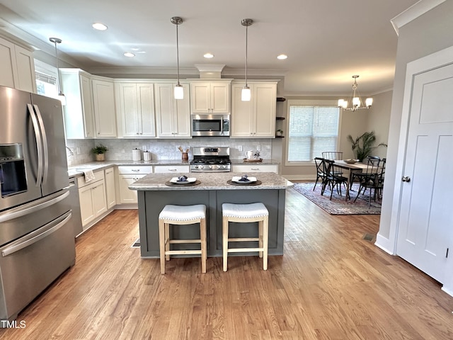 118 Chestnut St, Durham, NC 27707 - kitchen featuring appliances with stainless steel finishes, ornamental molding, tasteful backsplash, a chandelier, and a center island