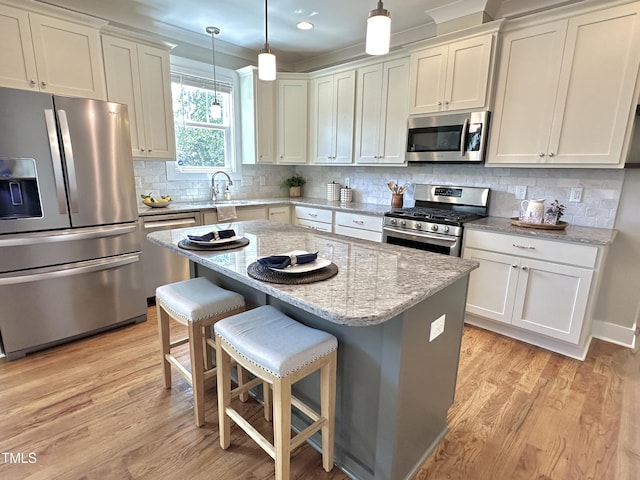 118 Chestnut St, Durham, NC 27707 - kitchen featuring stainless steel appliances, light wood-style flooring, a center island, light stone countertops, and a kitchen breakfast bar