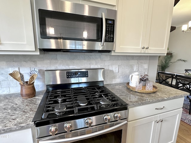 118 Chestnut St, Durham, NC 27707 - kitchen featuring stainless steel appliances, white cabinets, light stone counters, decorative backsplash, and wood finished floors
