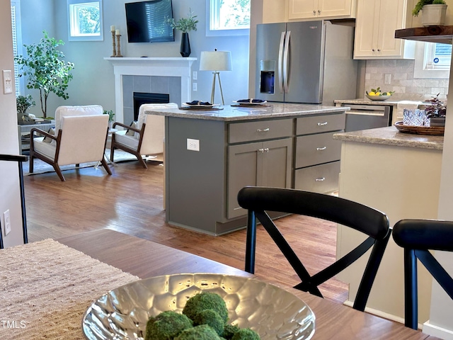 118 Chestnut St, Durham, NC 27707 - kitchen featuring appliances with stainless steel finishes, light wood-style floors, decorative backsplash, gray cabinets, and plenty of natural light
