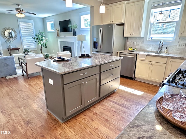 118 Chestnut St, Durham, NC 27707 - kitchen with appliances with stainless steel finishes, light wood-type flooring, open floor plan, a kitchen island, and gray cabinetry