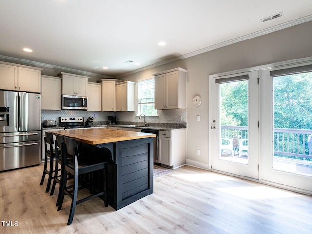 857 Stable Fern Dr, Fuquay Varina, NC 27526 - kitchen featuring appliances with stainless steel finishes, butcher block countertops, crown molding, tasteful backsplash, and a center island