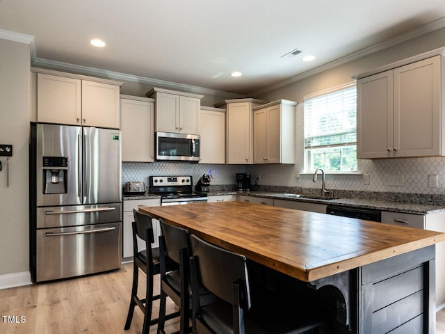 857 Stable Fern Dr, Fuquay Varina, NC 27526 - kitchen featuring appliances with stainless steel finishes, wood counters, crown molding, a breakfast bar, and light wood-style floors