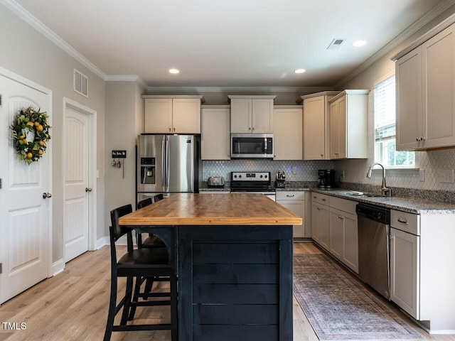 857 Stable Fern Dr, Fuquay Varina, NC 27526 - kitchen featuring appliances with stainless steel finishes, butcher block countertops, crown molding, decorative backsplash, and a center island