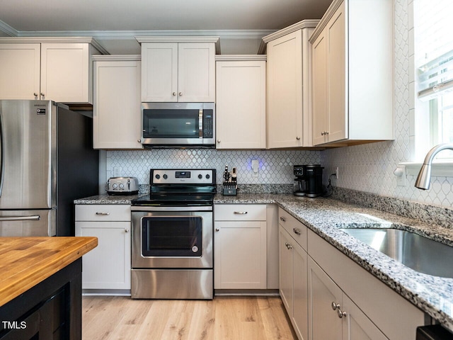 857 Stable Fern Dr, Fuquay Varina, NC 27526 - kitchen featuring stainless steel appliances, decorative backsplash, crown molding, light stone counters, and light wood finished floors