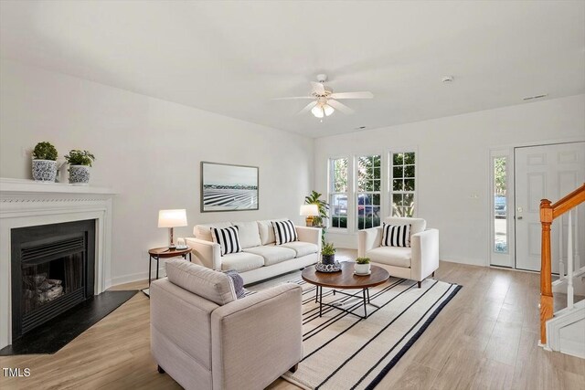 8326 Glenwood Springs Ct, Raleigh, NC 27616 - living area featuring ceiling fan, light wood-style floors, stairs, and a fireplace with flush hearth