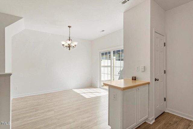 8326 Glenwood Springs Ct, Raleigh, NC 27616 - kitchen featuring light wood-style floors, a chandelier, a peninsula, hanging light fixtures, and light countertops