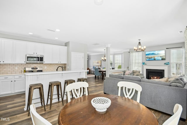 304 Forbes Rd, Wake Forest, NC 27587 - dining space with a chandelier, healthy amount of natural light, a warm lit fireplace, dark wood-style floors, and recessed lighting