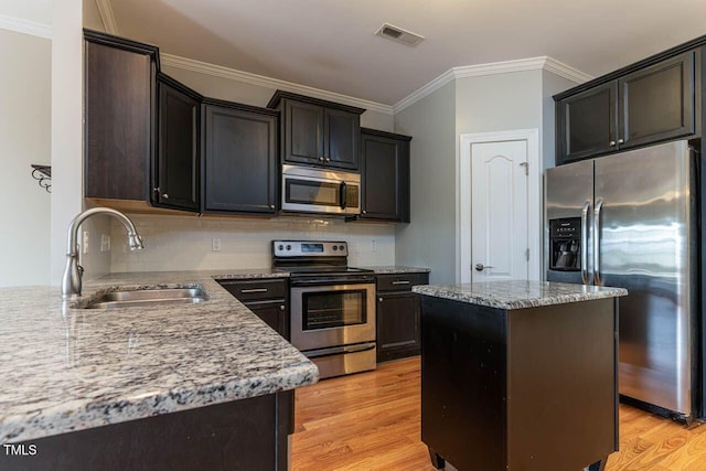 996 Tender Dr, Apex, NC 27502 - kitchen featuring stainless steel appliances, crown molding, light wood-type flooring, tasteful backsplash, and light stone countertops