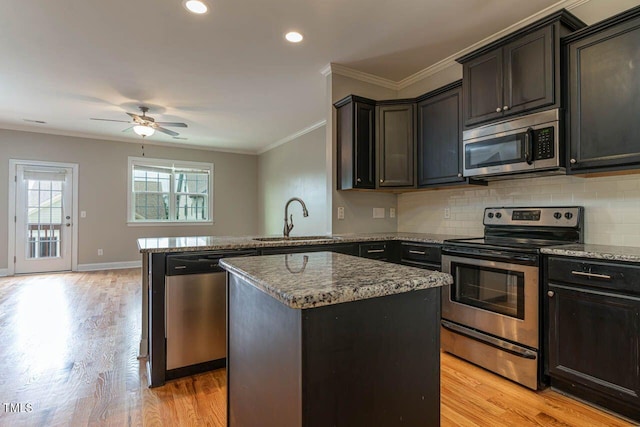 996 Tender Dr, Apex, NC 27502 - kitchen with appliances with stainless steel finishes, a peninsula, stone countertops, light wood finished floors, and decorative backsplash