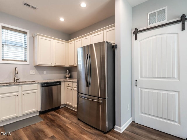 157 E Wilson St, Clayton, NC 27520 - kitchen with appliances with stainless steel finishes, a barn door, recessed lighting, dark wood finished floors, and white cabinets
