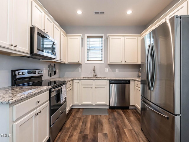 157 E Wilson St, Clayton, NC 27520 - kitchen featuring appliances with stainless steel finishes, white cabinetry, recessed lighting, dark wood-style flooring, and light stone counters